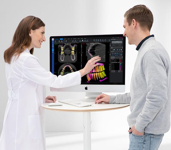 Dentista analisando tomografia e explicando o planejamento de implante dentário ao paciente.